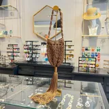 Bolso limosnero marrón tejido en macramé, con flecos largos y asa trenzada.