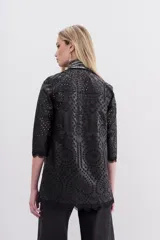Saco negro de símil cuero con bordado de flores y calado en toda la prenda. Tiene cuello redondo, mangas largas y apertura frontal con broches ocultos.