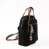 Mochila negra con bolsillo frontal con cierre, manija superior y tiras traseras regulables. Incluye llavero decorativo con cuentas de colores.