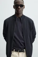 Cárdigan negro de punto con cuello perkins, cierre frontal con cremallera, manga larga y corte regular fit.