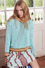 Sweater tejido a mano de algodón color celeste, con cuello redondo y puños con terminaciones bordadas en colores.