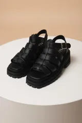 Sandalias negras de cuero con plataforma y tiras anchas entrecruzadas.