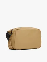 Bandolera Tommy Hilfiger color beige con logo texturizado en el frente. Tiene correa ajustable de tejido trenzado, cierre de cremallera y bolsillo exterior con cremallera.