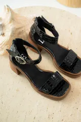 Sandalias de cuero color crudo, con tira ancha sobre los dedos, pulsera con hebilla al tobillo y taco cuadrado de madera.