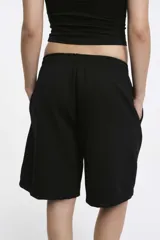 Short deportivo negro con cintura elástica y bolsillos laterales. Corte holgado a la rodilla.