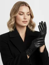 Guantes de cuero sintético color camel, con forro interior de terciopelo. Presentan un diseño clásico con costuras decorativas en el dorso y una tira ajustable con botón a presión en la muñeca.