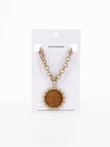 Collar dorado con charm central de diseño circular y cadena de eslabones.