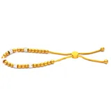 Pulsera dorada con cuentas redondas y cilíndricas con incrustaciones de strass, ajustable con cierre corredizo.