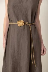 Cinto fino color beige, de cordón trenzado con detalle de flor tejida al crochet.