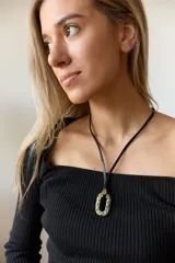 Collar con doble tira de tiento negro, una ajustada al cuello como choker y otra más larga con un dije ovalado de piedra natural blanca y un pequeño detalle dorado.