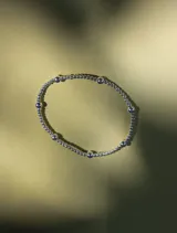 Pulsera elástica compuesta por pequeñas cuentas plateadas de 2 mm y cuentas más grandes de 4 mm espaciadas a lo largo de la circunferencia.