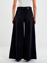 Jeans de denim negro con lavado oscuro, tiro alto y pierna muy ancha (palazzo o culotte muy largo). Presenta cierre clásico de botón y cremallera, y bolsillos delanteros y traseros.