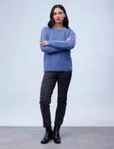 Buzo de tejido melange color beige con puntos oscuros, cuello redondo y manga larga.