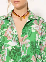Camisa de viscosa con estampado de hongos en tonos verdes, celestes y rosados. Tiene corte relajado, cartera oculta y botones de pasta teñidos a tono con logo marcario.