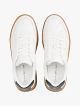 Zapatillas Tommy Hilfiger blancas de cuero, con suela marrón y detalle azul en el talón.