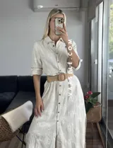 Vestido camisero midi color crudo con bordado floral, cuello camisero, mangas 3/4 con trabilla y abertura lateral. Incluye cinturón de soga con hebilla de madera.