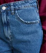 Short mom en jeans azul con barra doblada, tiro alto, bolsillos delanteros y traseros, y cierre con cremallera y botón.