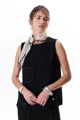 Top sin mangas color terracota con cuello redondo y bolsillo frontal. Presenta costuras a contratono en blanco que definen los bordes y el bolsillo.