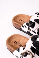 Zuecos con estampado de vaca en blanco y negro, con hebilla metálica ajustable y plantilla de corcho.