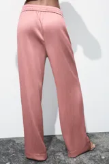 Pantalón de tiro alto color rosado, con cintura elástica ajustable con cordones, bolsillos delanteros y pernera ancha. Tejido con efecto arrugado.