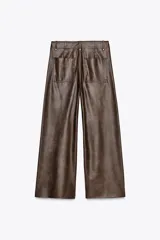 Pantalón marrón de tiro alto con efecto cuero, bolsillos de parche en la parte trasera y costuras marcadas en la parte delantera. Cierre frontal con cremallera y gancho metálico.