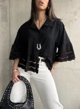 Camisa negra de mangas cortas con detalle de encaje en mangas y ruedo.
