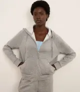 Campera deportiva gris confeccionada en microfibra, con capucha con cordón, cierre delantero, bolsillos y mangas largas.