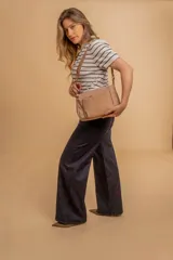 Bandolera de diseño moderno, color beige rosado, con correa regulable y bolsillo frontal con cierre.