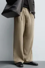 Pantalón negro de corte relajado con cintura elástica ajustable y pliegues en la parte delantera. Presenta bolsillos laterales y bolsillos traseros de parche.