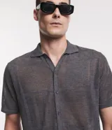 Camisa de punto gris con cuello inglés, mangas cortas, abotonadura frontal y textura geométrica.