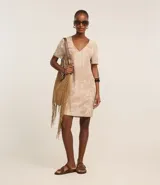 Vestido corto tipo t-shirt color beige con estampado de follaje y arquitectura, escote en V y mangas cortas.