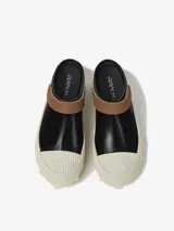 Zuecos negros de piel vacuna vulcanizada, con tiras marrones en la abertura, plantillas OrthoLite Recycled y suelas blancas de goma dentada.