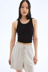 Short color beige de tiro alto con cintura elástica fruncida con ribete de volado, cordón para ajustar fino con cuentas de metal y bolsillos laterales discretos.