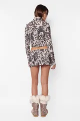 Minifalda de sarga gamuzada con estampado animal print, cierre frontal metálico y recortes horizontales con cierres laterales.