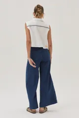 Blusa blanca de lino con cuello camisero, sin mangas, cierre frontal con botones y bordados en el frente.