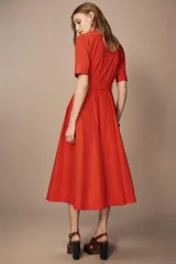 Vestido midi camisero color ladrillo, confeccionado en popelina de algodón. Presenta cuello solapa, manga corta con puños abotonados, bolsillos laterales ocultos y bolsillos de parche con solapa en el pecho. Incluye cinturón lazada en el mismo tejido y cierre frontal con botones ocultos.