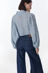 Camisa marrón con estampado de flores blancas, de corte cropped con nudo frontal y mangas largas abullonadas.