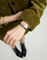 Pulsera de cuero marrón con doble tira y cristal facetado gris en el centro, engarzado en metal plateado.