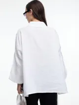 Camisa de lino color negro con silueta amplia y mangas 3/4. Diseño con tiras de color blanco en contraste en la cartera, mangas y cuerpo. Tiene tajos laterales y ruedo irregular en el frente.