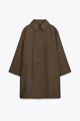 Trench color marrón con cuello solapa y manga tres cuartos. Tiene bolsillos delanteros y cierre frontal con cremallera y botones ocultos por solapa.