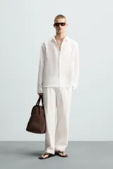 Camisa de manga larga color celeste claro, con cuello solapa y cierre frontal de botonadura. Presenta una textura sutil en el tejido.