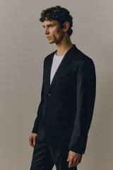 Blazer negro de corte slim fit, con solapas de muesca finas, ojal decorativo, botonadura sencilla, bolsillo superior insertado, bolsillos delanteros con solapa, dos bolsillos interiores, botones decorativos en los puños y abertura doble atrás. Forrado.