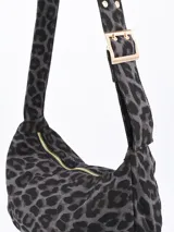 Cartera bandolera con estampado animal print en tonos grises y negros. Tiene correa corta ajustable con hebilla dorada y cierre superior con cremallera dorada.