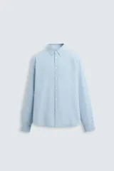 Camisa celeste de corte regular fit, confeccionada en popelín de algodón. Tiene cuello abotonado, manga larga con puños abotonados y cierre frontal con botones.