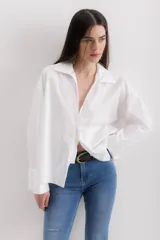 Camisa blanca de algodón con cuello clásico, mangas largas con puños abotonados y bolsillo de parche en el frente.