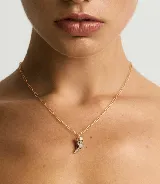 Collar dorado con cadena de eslabones alargados y dije en forma de cuerno con incrustaciones de cristales negros.