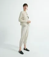Pantalón jogger color beige, con elástico en la cintura y en los tobillos, cordón ajustable, bolsillos laterales y detalles de agujeros en los laterales y en los bolsillos.