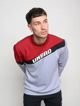 Buzo deportivo Umbro gris con mangas y parte superior en rojo. Presenta una franja diagonal negra con el logo de la marca en blanco.