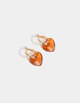 Aros dorados tipo argolla con dije de corazón de resina color naranja.