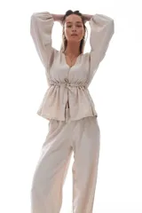 Blusa color crema con escote en V, mangas largas abullonadas y cintura ajustable con cordón.